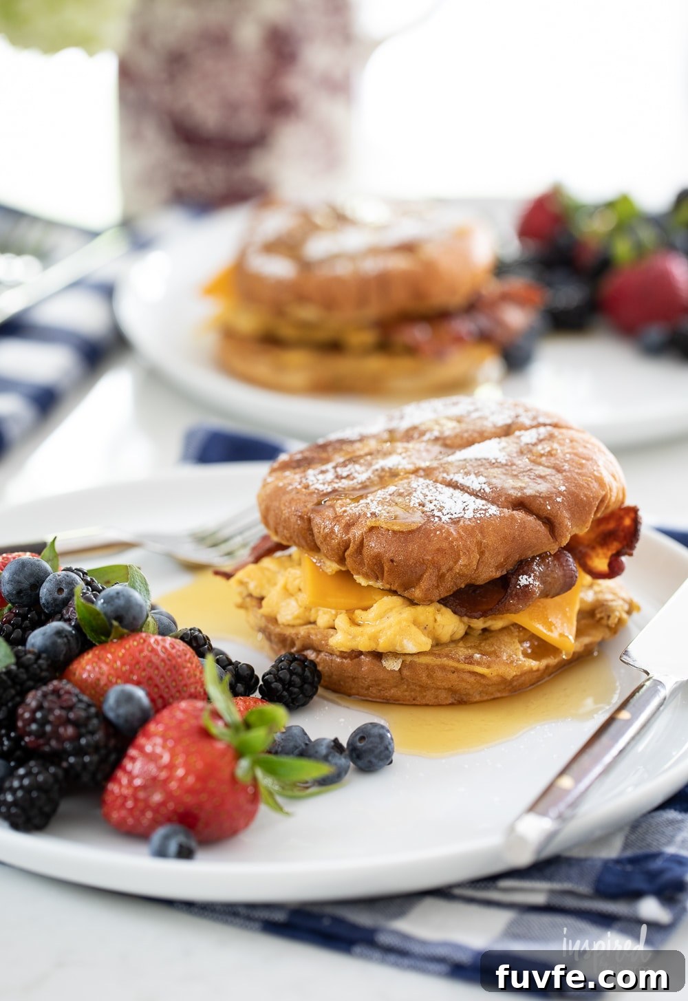 up close french toast breakfast sandwiches on plates on gingham napkins.