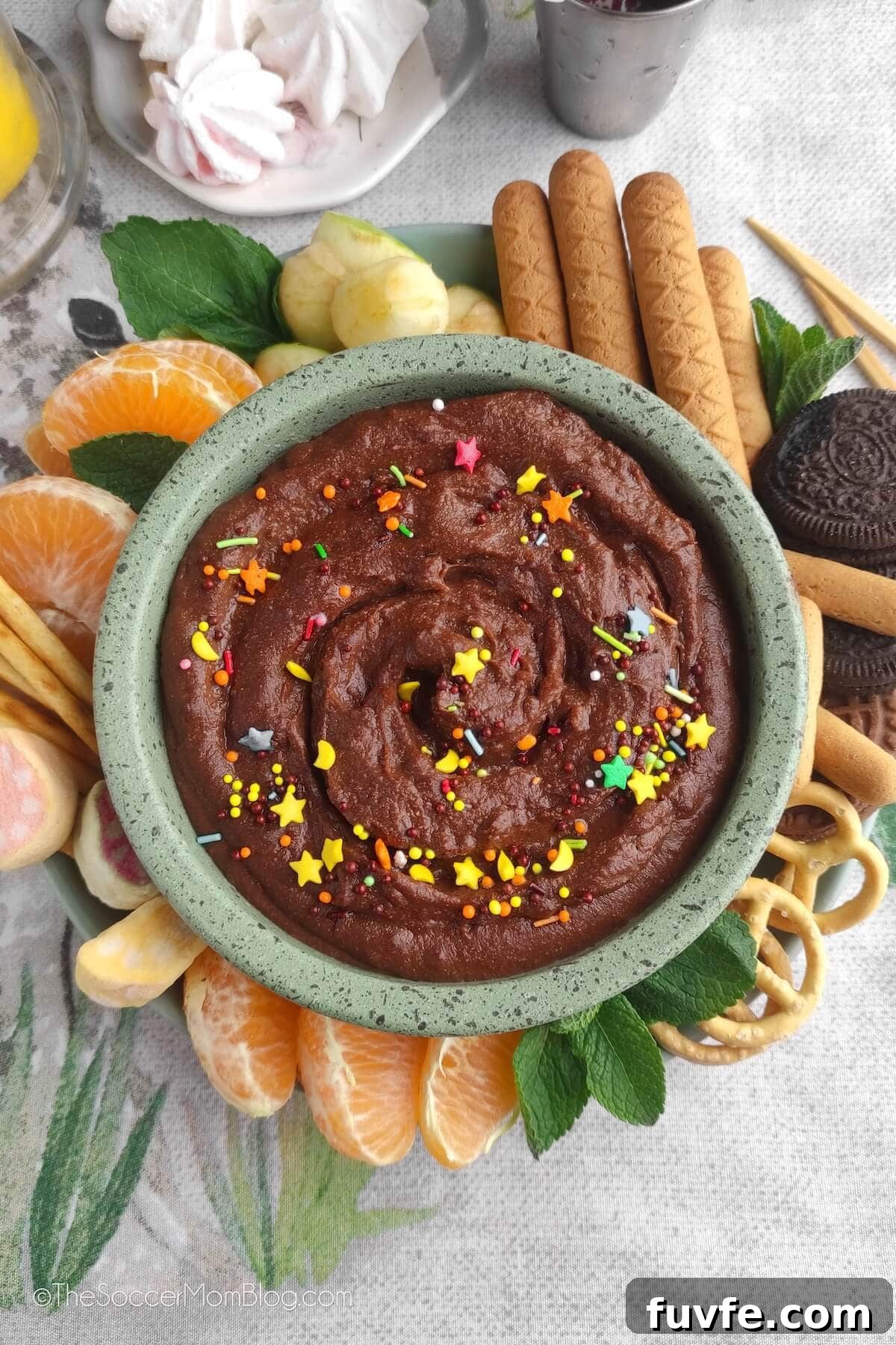 bowl of chocolate hummus dip, with fruit and pretzels 