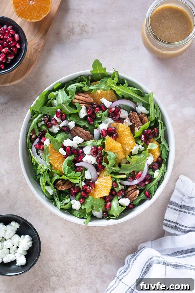 Arugula pomegranate salad in a bowl with pomegranate dressing and linen