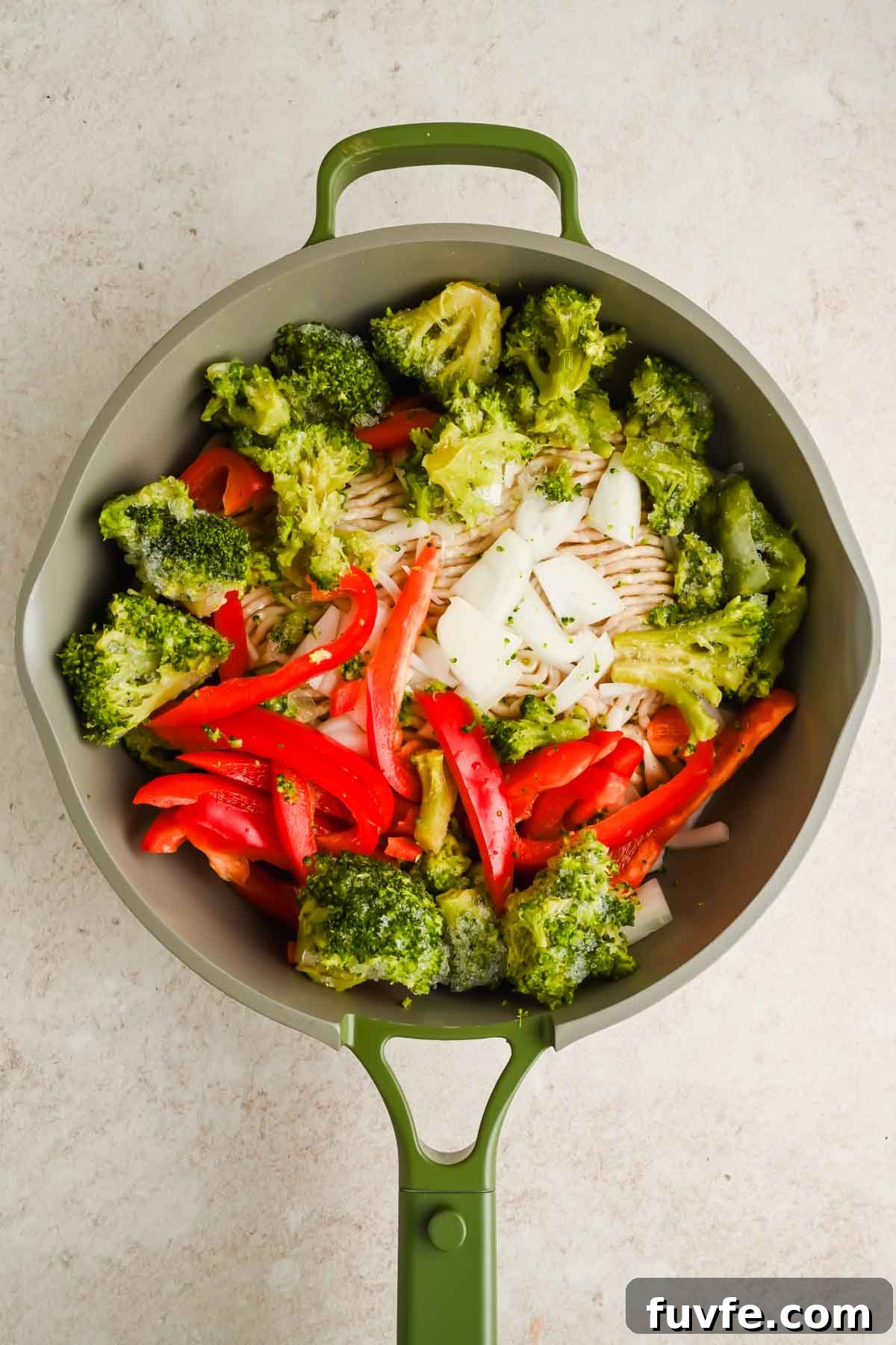 raw veggies and ground chicken in green skillet.