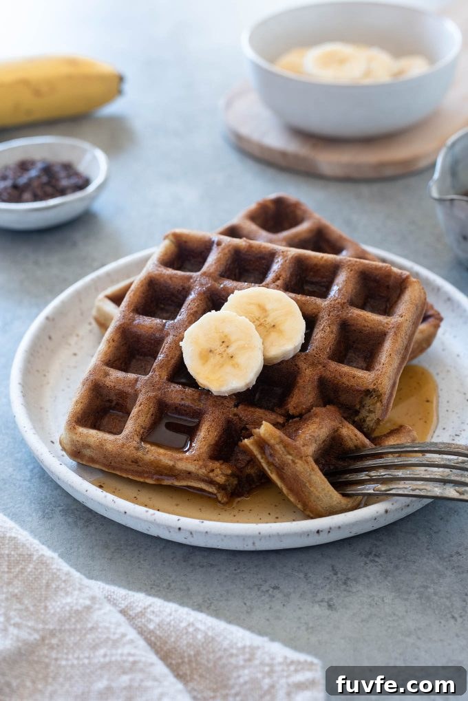 Fluffy Gluten-Free Banana Oat Waffles Recipe 2 Waffles on a plate with sliced banana on top