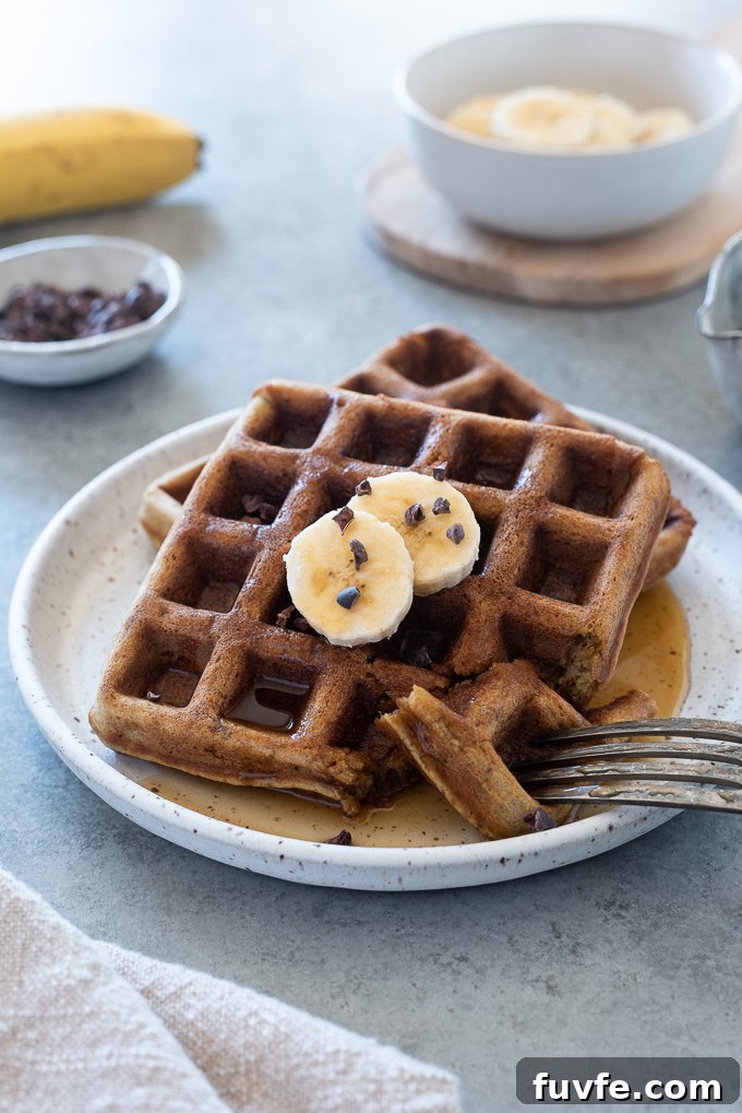 Fluffy Gluten-Free Banana Oat Waffles Recipe 7 Banana oat waffles on a plate with banana and cacao nibs on top