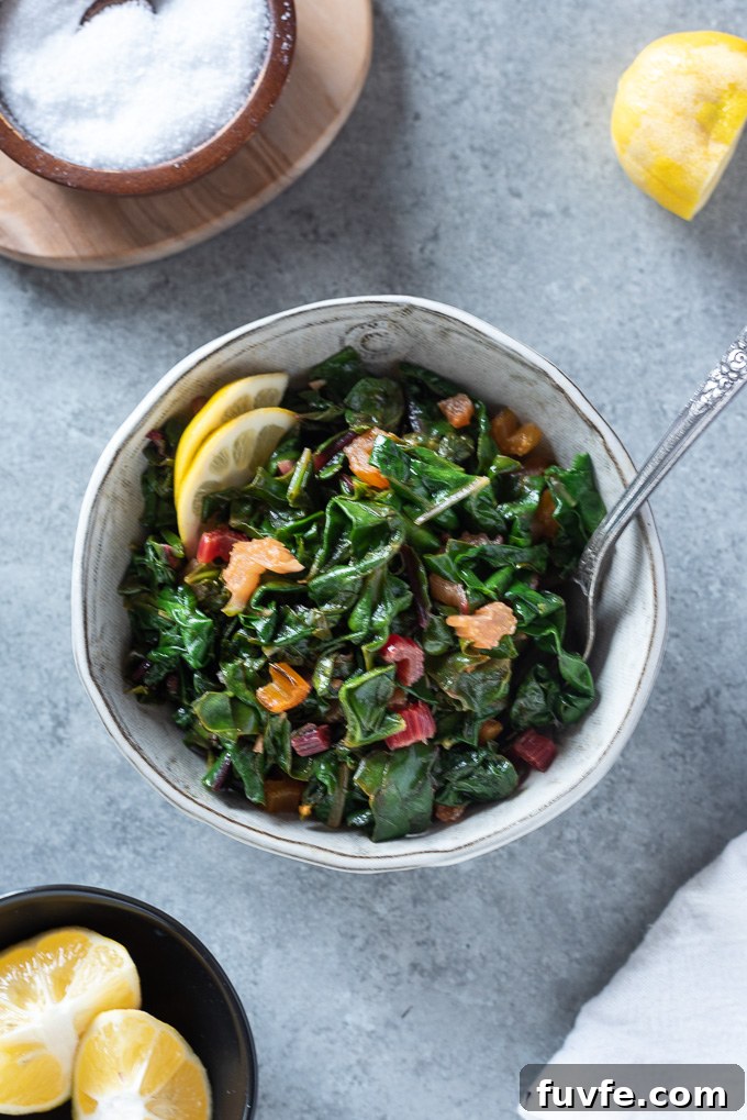 Sautéed swiss chard in a white bowl with a fork digging in