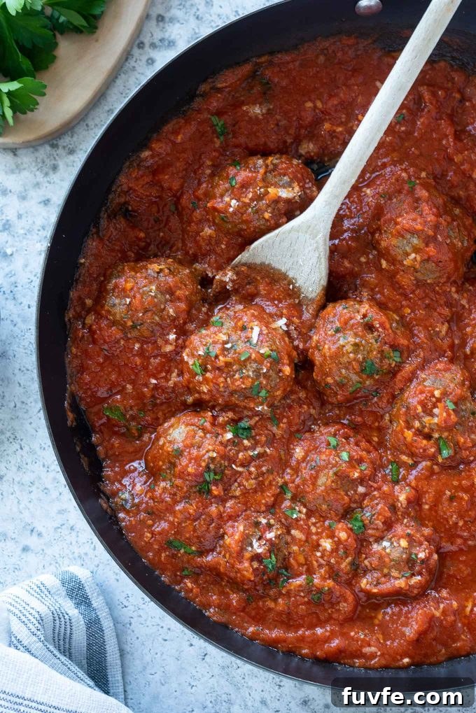Oven baked meatballs in a skillet with tomato sauce