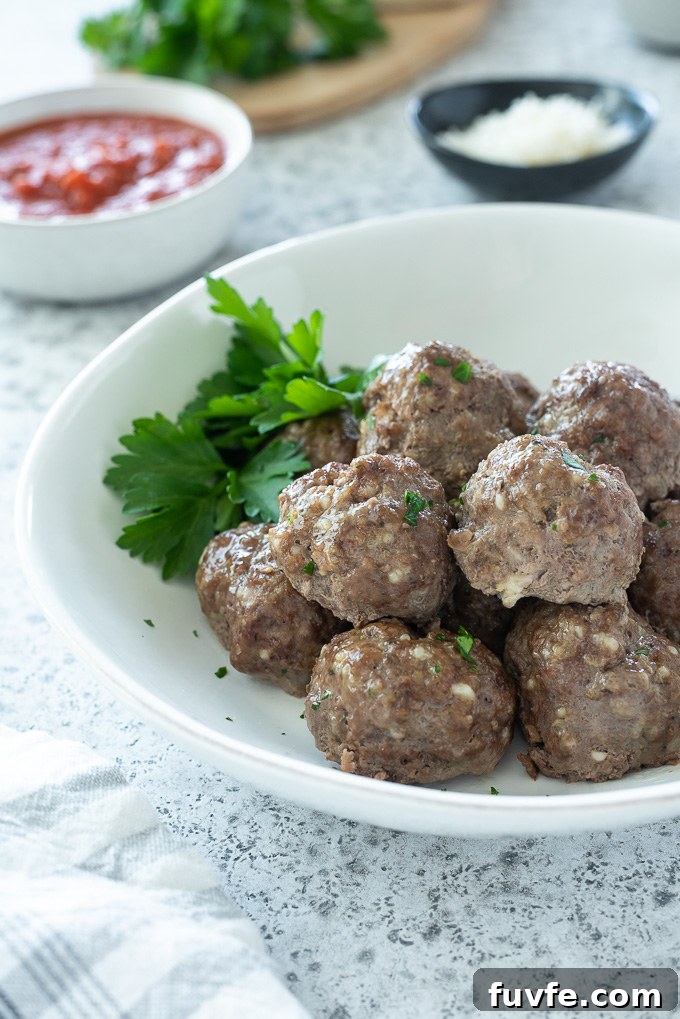 Ground beef meatballs in a white bowl with parsley