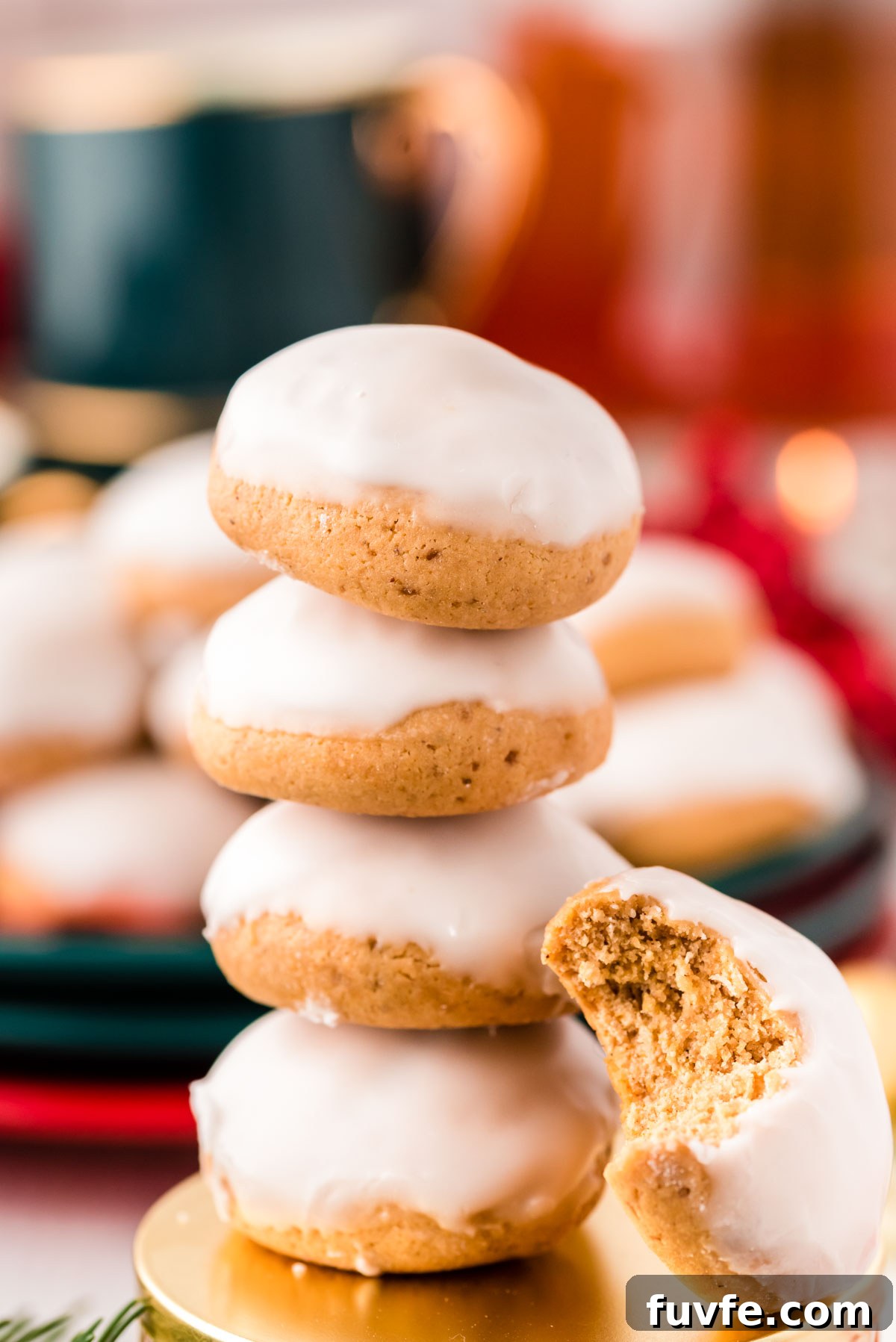 Stack of 4 pfeffernusse cookies with one cookie with a bite taken out of it leaning against the stack.