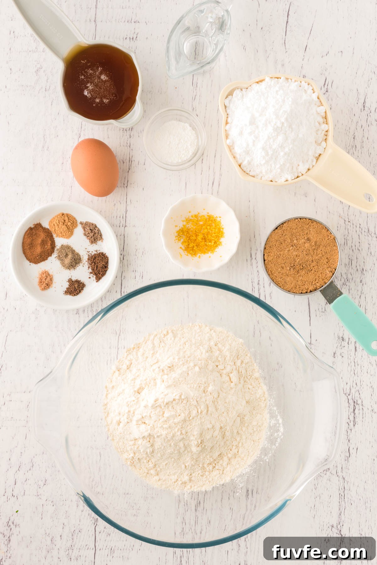 Overhead photo of the ingredients to make pfeffernusse cookies on a white wooden table.