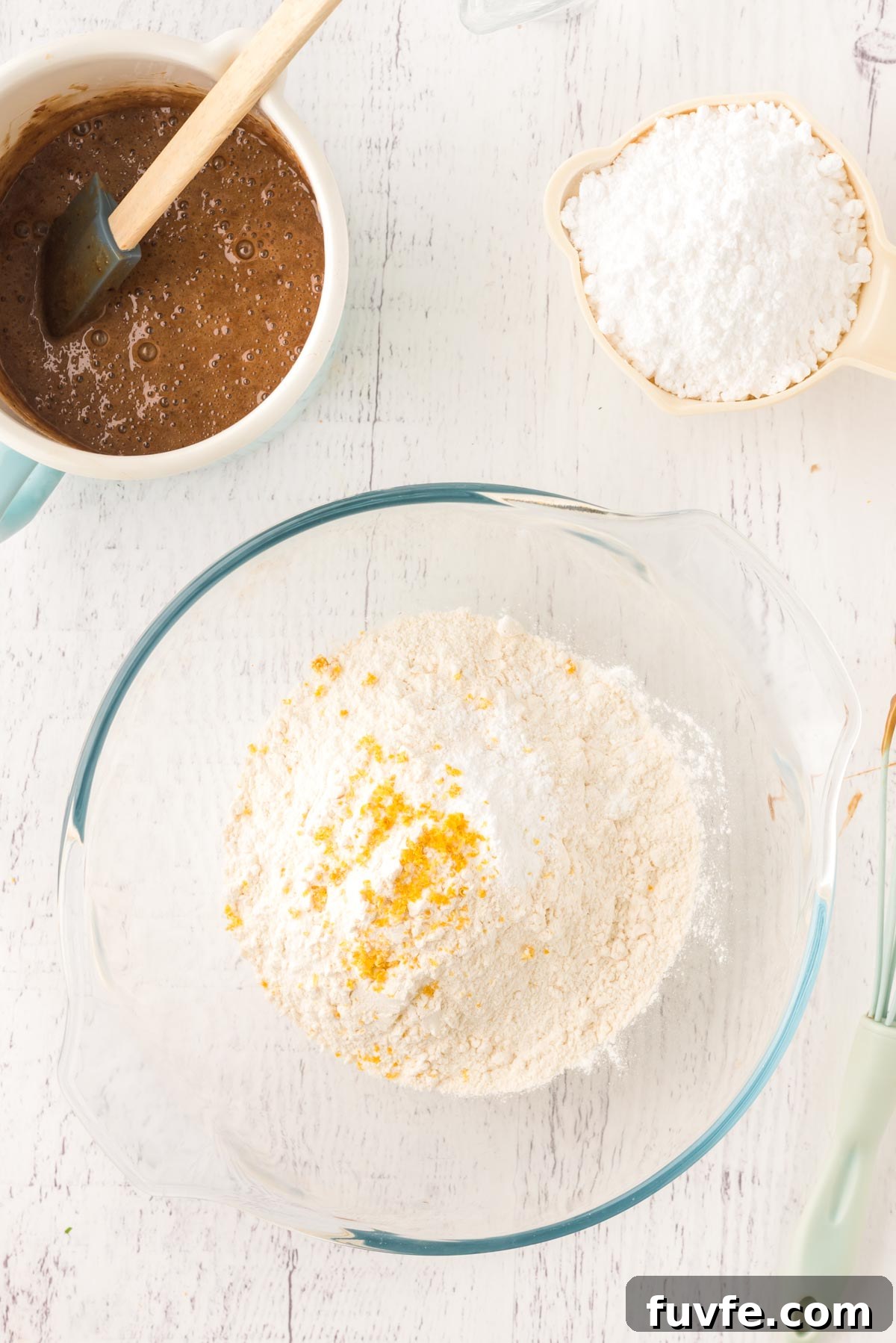 Overhead photo of a glass mixing bowl with flour and lemon zest in it.