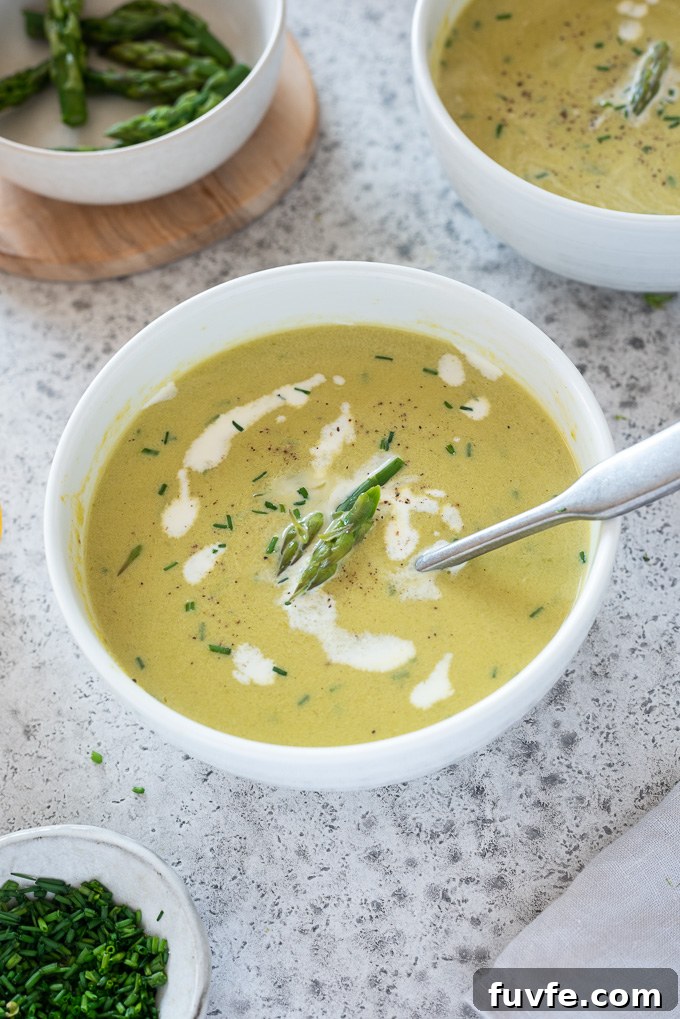 asparagus leek soup in a white bowl with spoon buried in it