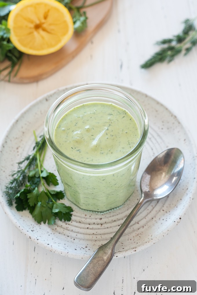Green Goddess dressing in a jar with herbs and a spoon