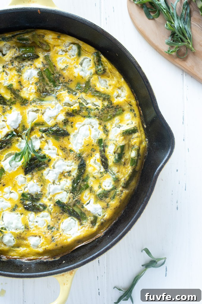Asparagus frittata in a skillet with goat cheese and tarragon