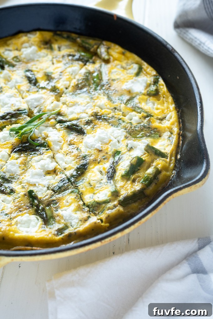 Asparagus frittata with goat cheese sliced in a cast iron skillet