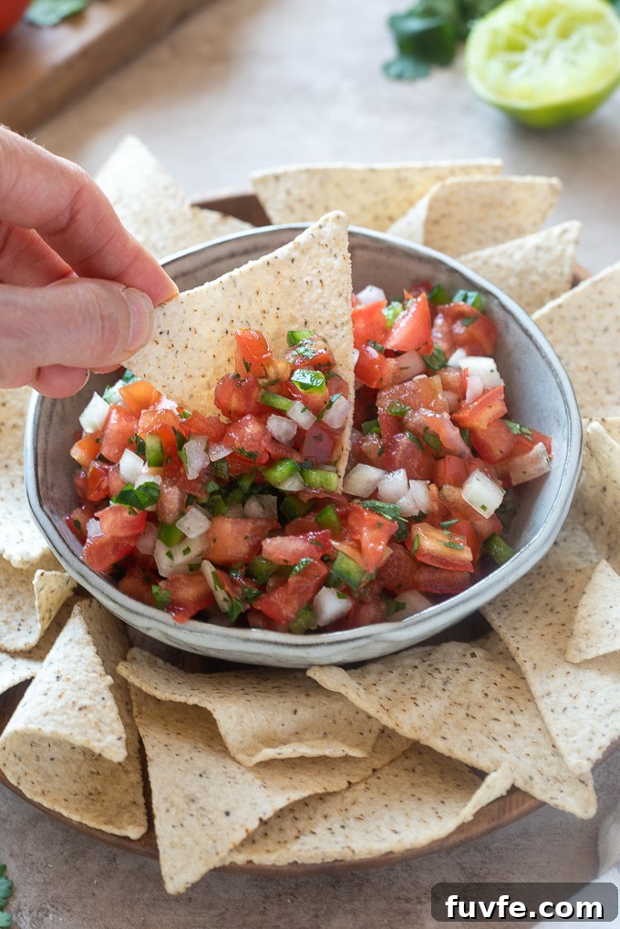 Tortilla chip dipping into a bowl of pico de gallo
