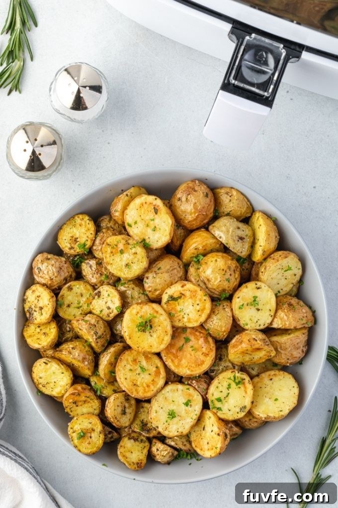 Crispy Air Fryer Potatoes with Garlic and Herbs 3 Air fryer roasted potatoes in a bowl by an air fryer