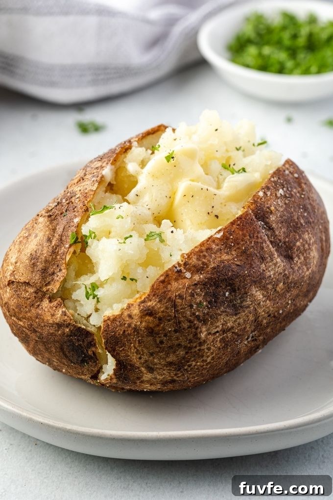 Air fryer baked potato on a plate with melted butter