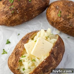 Air fryer baked potatoes with pats of butter and parsley