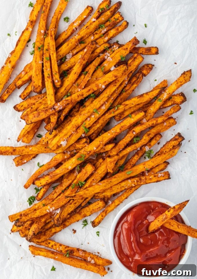 Air fryer sweet potato fries on parchment with ketchup.