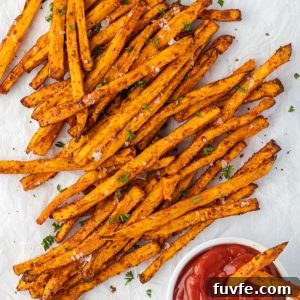 Air fryer sweet potato fries on parchment with ketchup.
