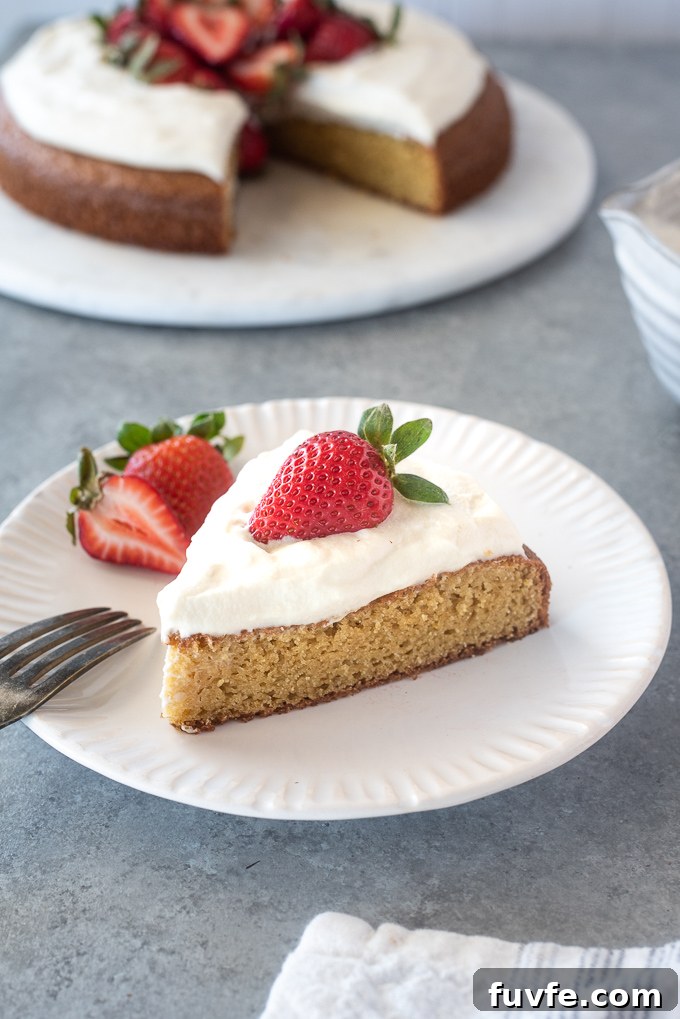 Slice of almond flour cake on a plate with whipped cream and strawberry