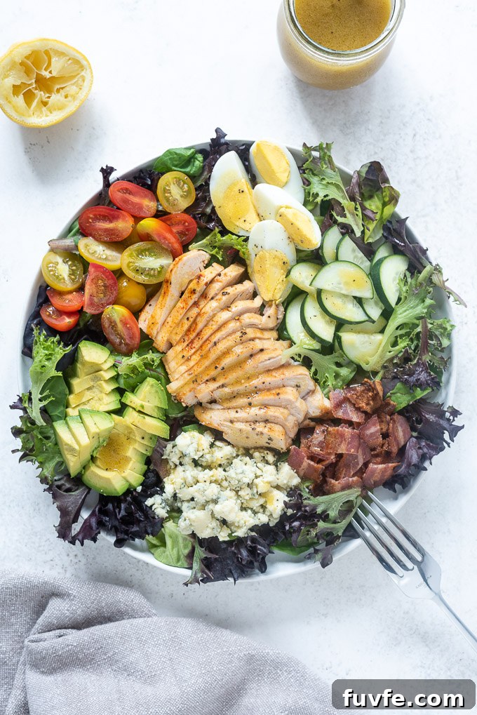Classic Chicken Cobb Salad Recipe with Avocado and Bacon 6 Chicken cobb salad in a white bowl with a fork
