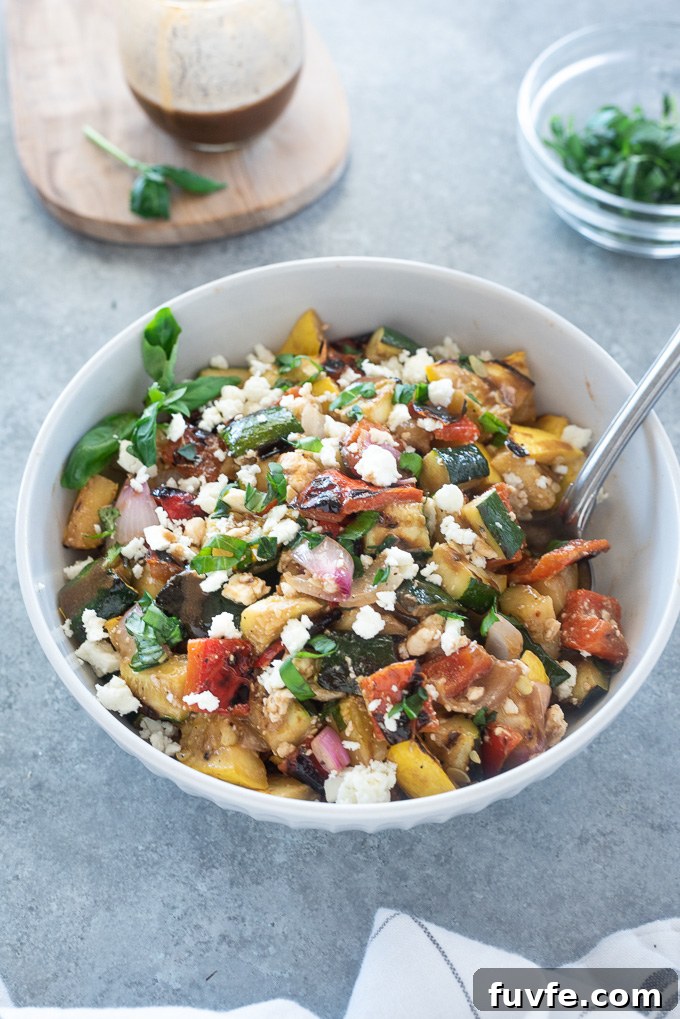 Grilled Vegetable Salad with Balsamic Herb Vinaigrette 7 Grilled vegetable salad in a white bowl with serving spoon
