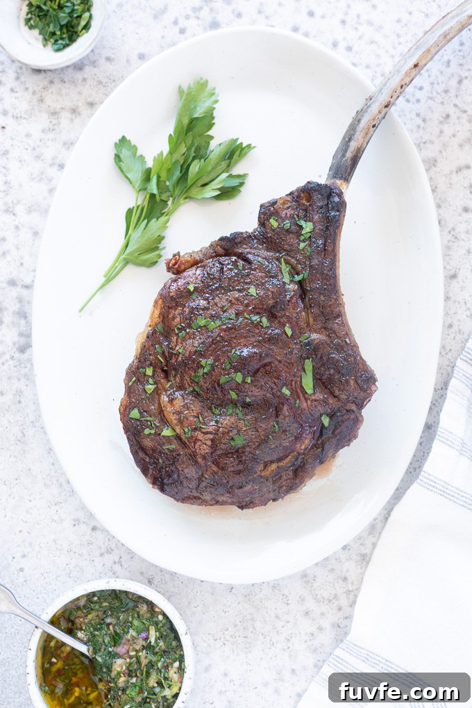 Tomahawk steak on a white platter with parsley