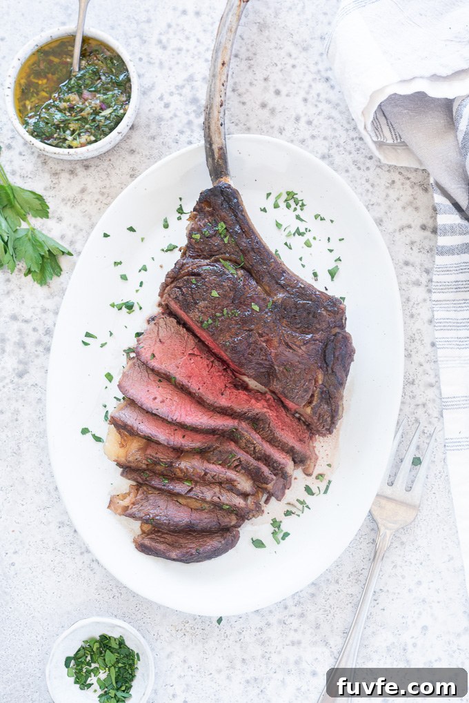 Grilled tomahawk steak sliced on a platter finished with chopped parsley