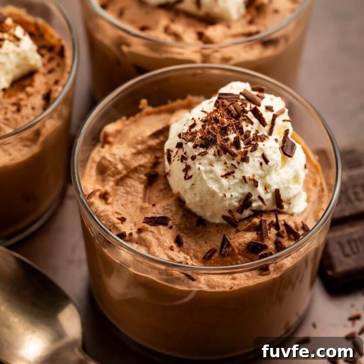 Low-Carb Keto Chocolate Mousse Recipe for Rich Guilt-Free Dessert 4 Three glass cups of keto chocolate mousse topped with keto whipped cream and chocolate shavings.