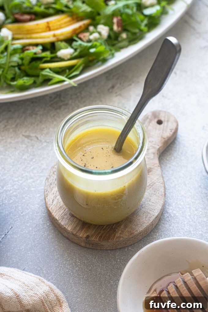 Honey champagne vinaigrette in a jar with a spoon.
