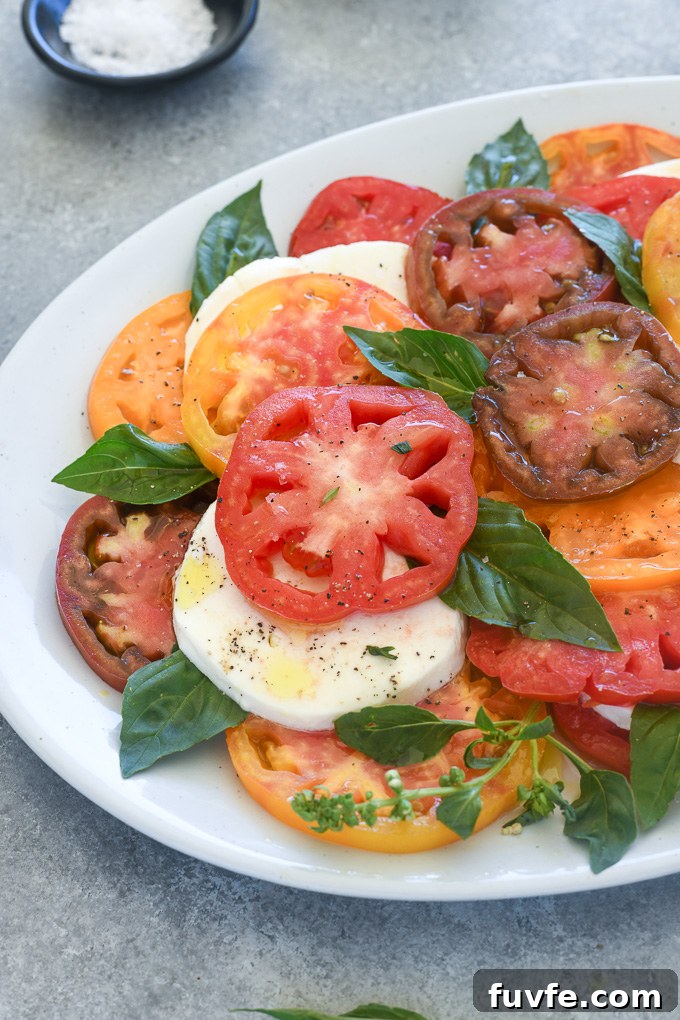 Classic Caprese Salad with Fresh Mozzarella and Balsamic Glaze 3 Tomato mozzarella salad layered on a white platter with basil
