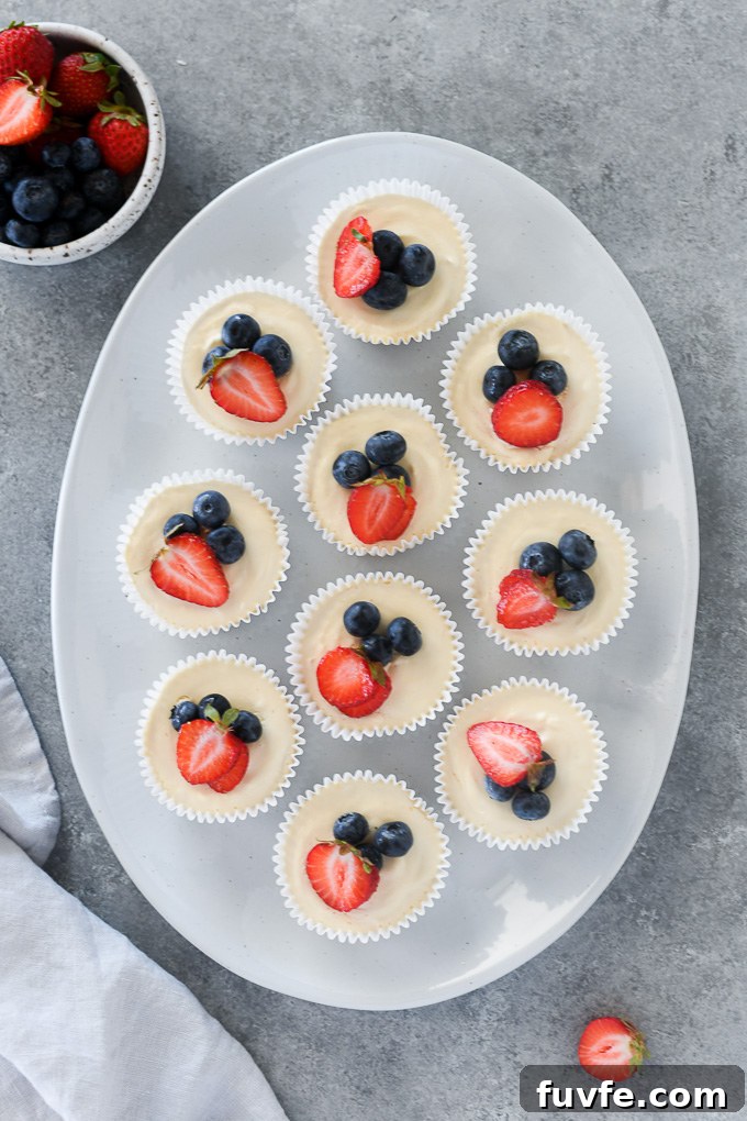 Mini no bake cheesecakes on a platter topped with berries