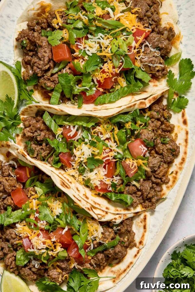 Quick Ground Beef Tacos Recipe for Weeknights 3 Tacos with ground beef on a platter with lime and cilantro.
