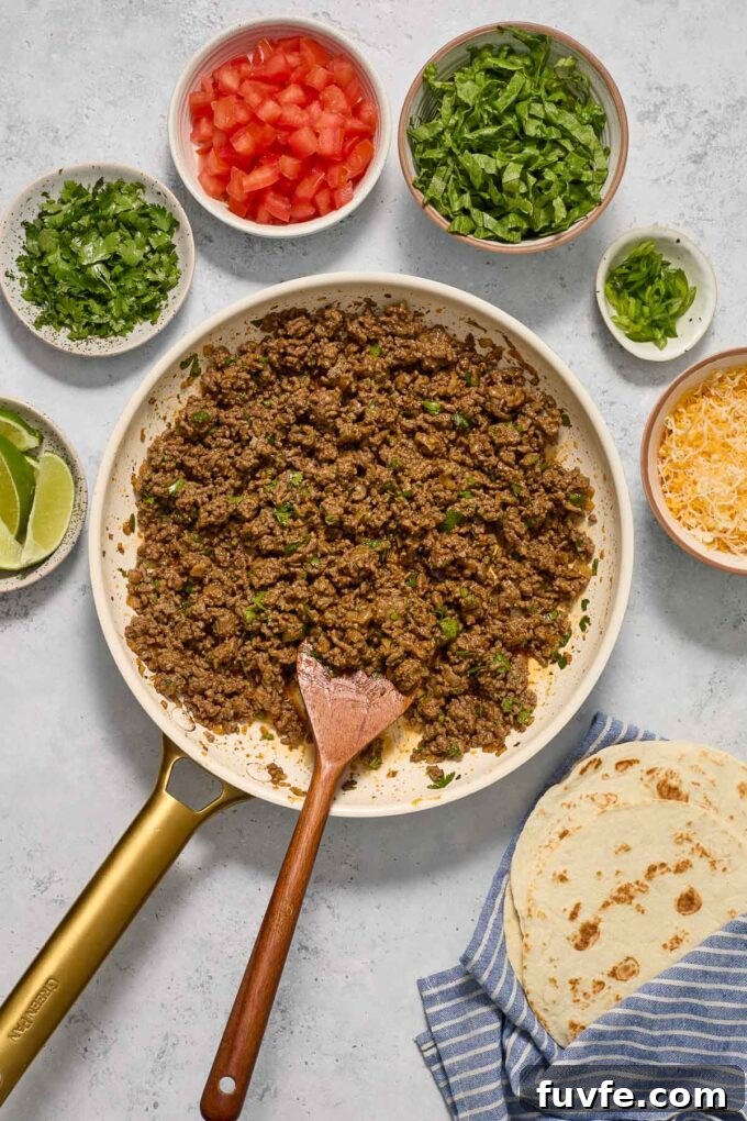 Quick Ground Beef Tacos Recipe for Weeknights 6 Ground beef taco meat in a skillet surrounded by condiments.