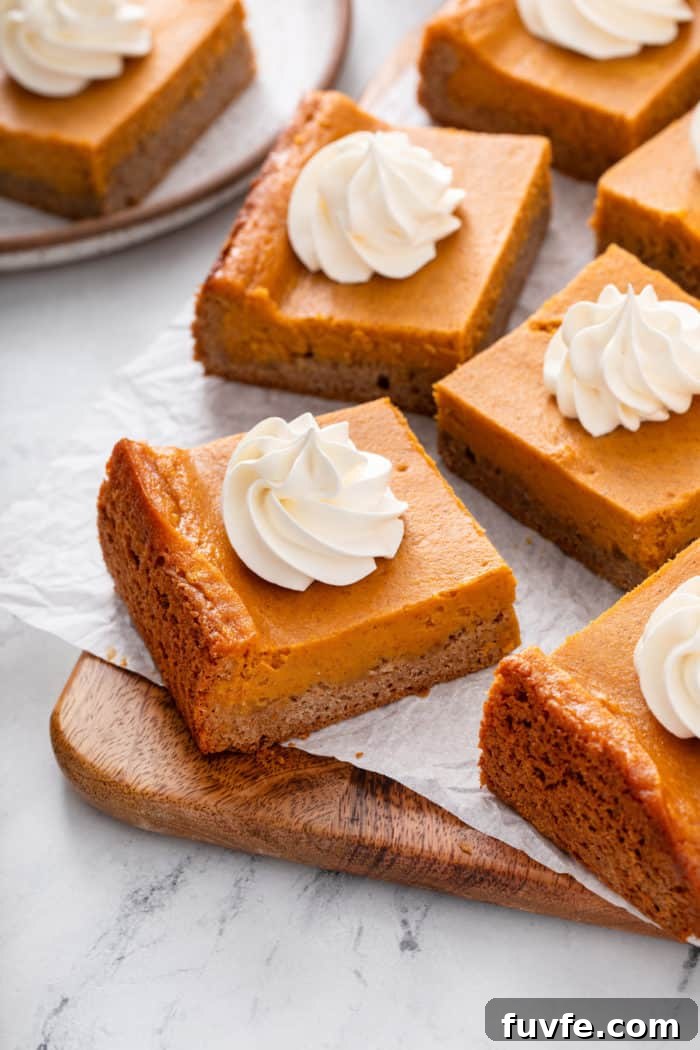 Pumpkin Gooey Butter Cake Recipe — Decadent Fall Dessert 2 Several slices of pumpkin gooey butter cake arranged on a parchment-lined cutting board.