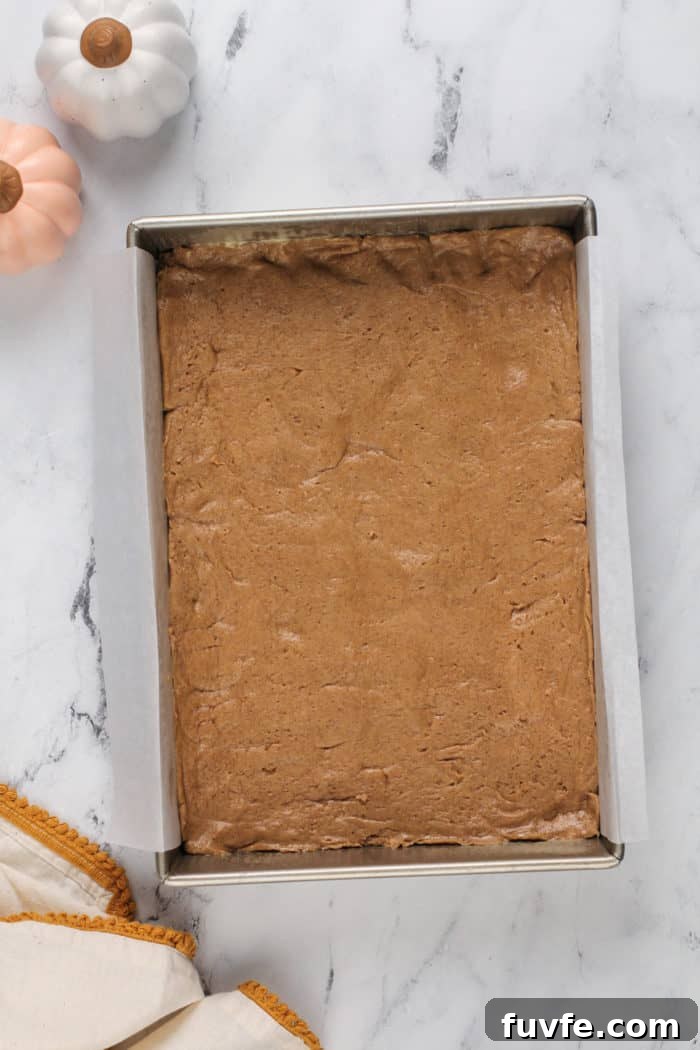 Pumpkin Gooey Butter Cake Recipe — Decadent Fall Dessert 7 Spice cake crust pressed into a parchment-lined cake pan.