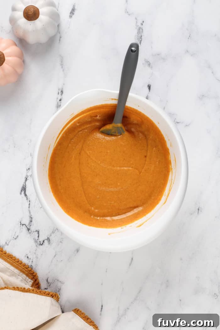 Pumpkin Gooey Butter Cake Recipe — Decadent Fall Dessert 8 Pumpkin filling for pumpkin gooey butter cake in a white mixing bowl.