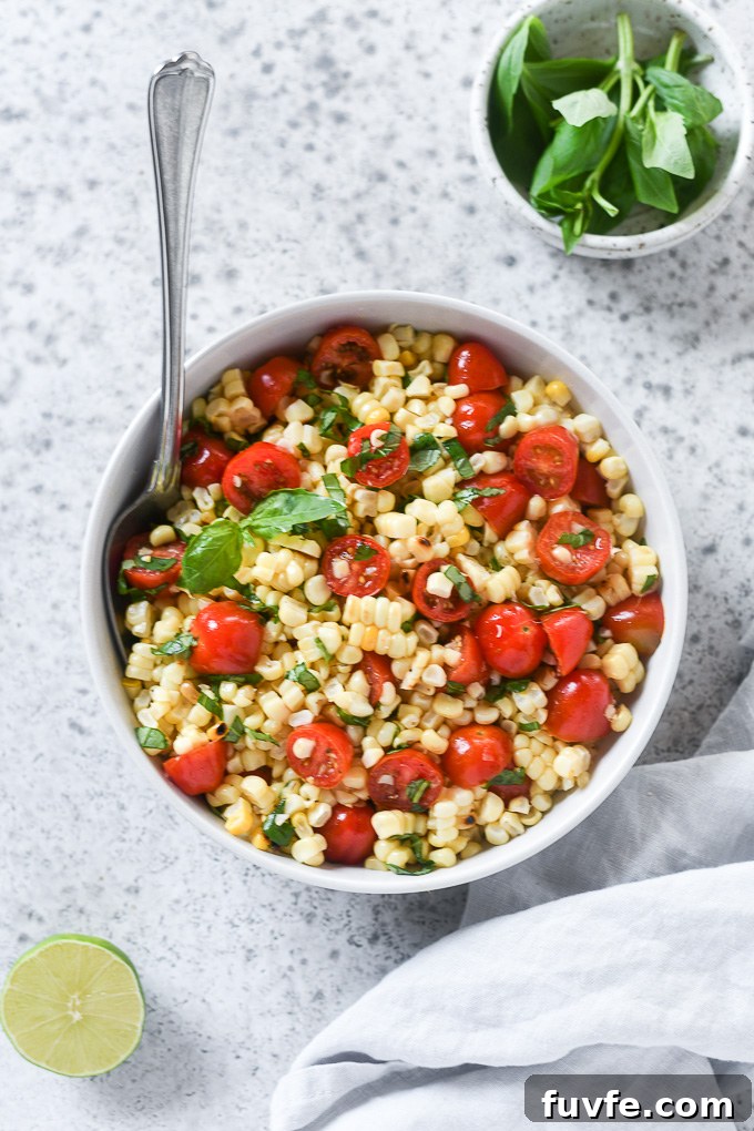 Tomato corn salad in a white bowl with basil