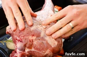 Rubbing olive oil over a leg of lamb using hands