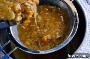 Pouring the leg of lamb juices and veg in to a sieve to form a lamb gravy