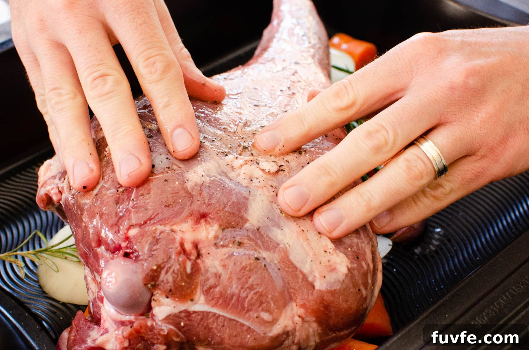 Rubbing olive oil over a leg of lamb using hands