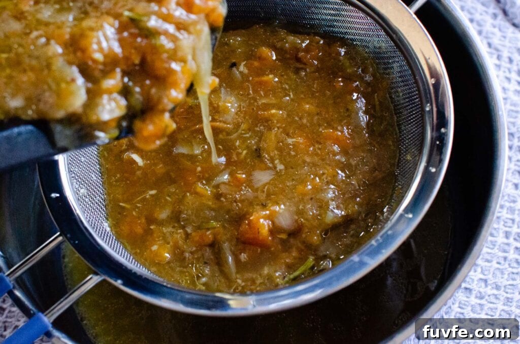 Pouring the leg of lamb juices and veg in to a sieve to form a lamb gravy