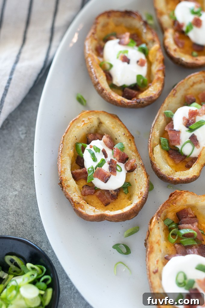 Loaded potato skins on a platter with scallions