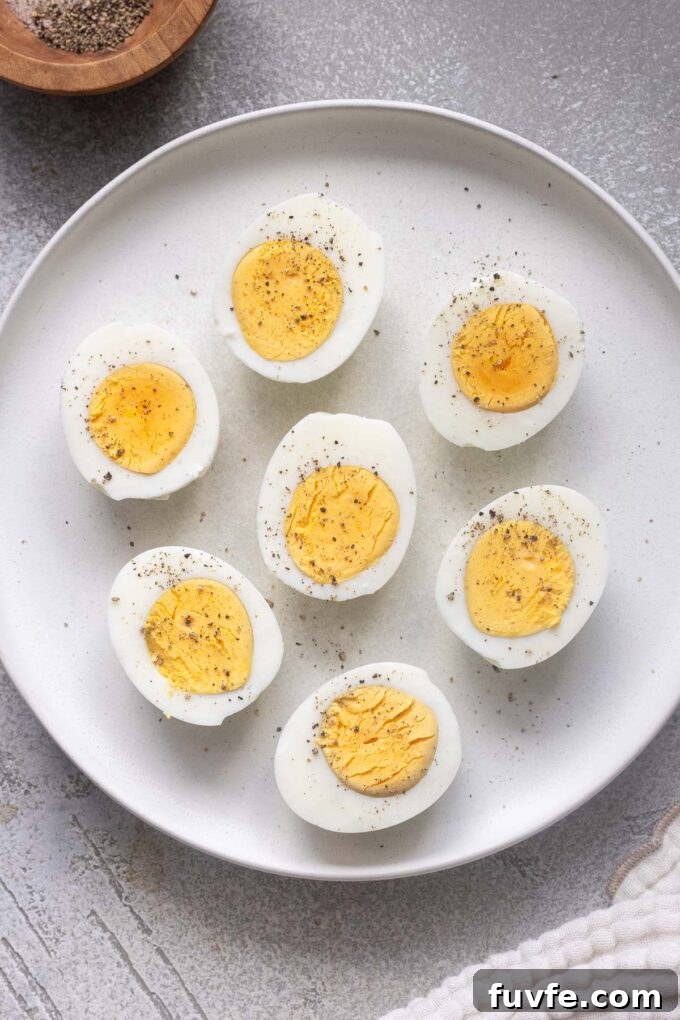 Air fryer hard boiled eggs cut in half with perfectly cooked yolks on a plate.