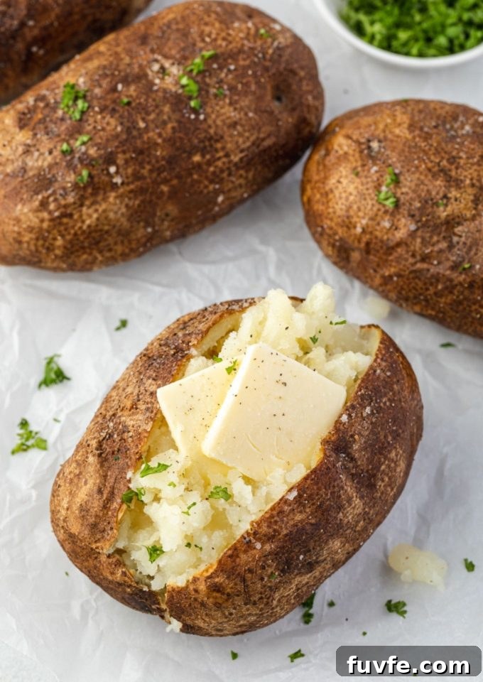 Air fryer baked potatoes with pats of butter and parsley