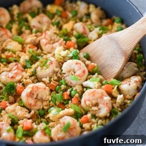 Authentic Shrimp Fried Rice Recipe with Garlic and Scallions 8 Wooden spoon digging into pan of shrimp fried rice