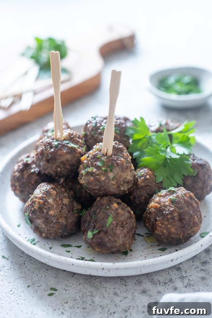 Crispy Air Fryer Meatballs Recipe 2 Air fryer meatballs on a plate with parsley