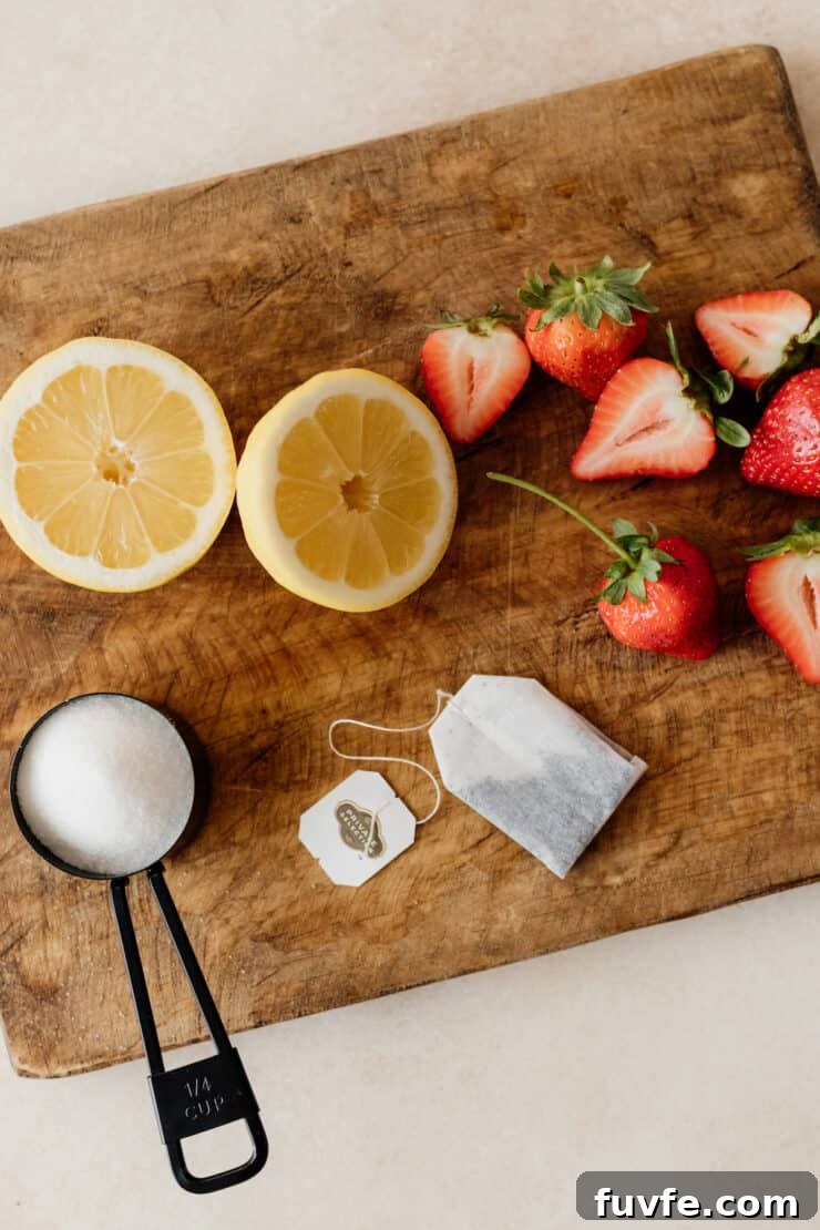 tea bag, sugar, halved lemon and strawberries on a wooden board