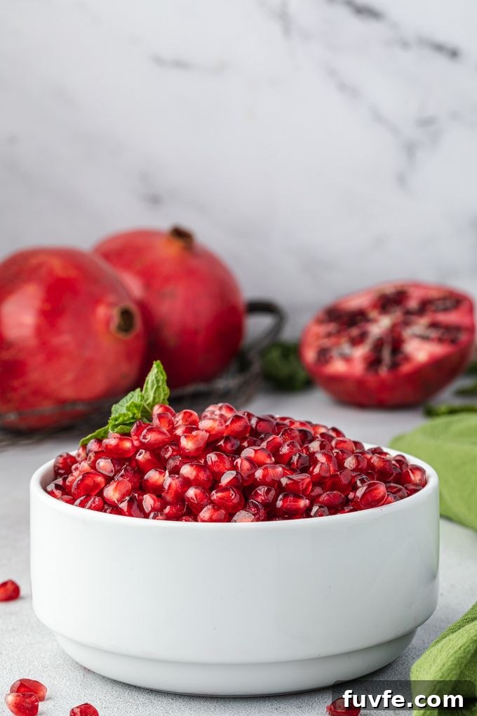 Pomegranate seeds in a white bowl with mint