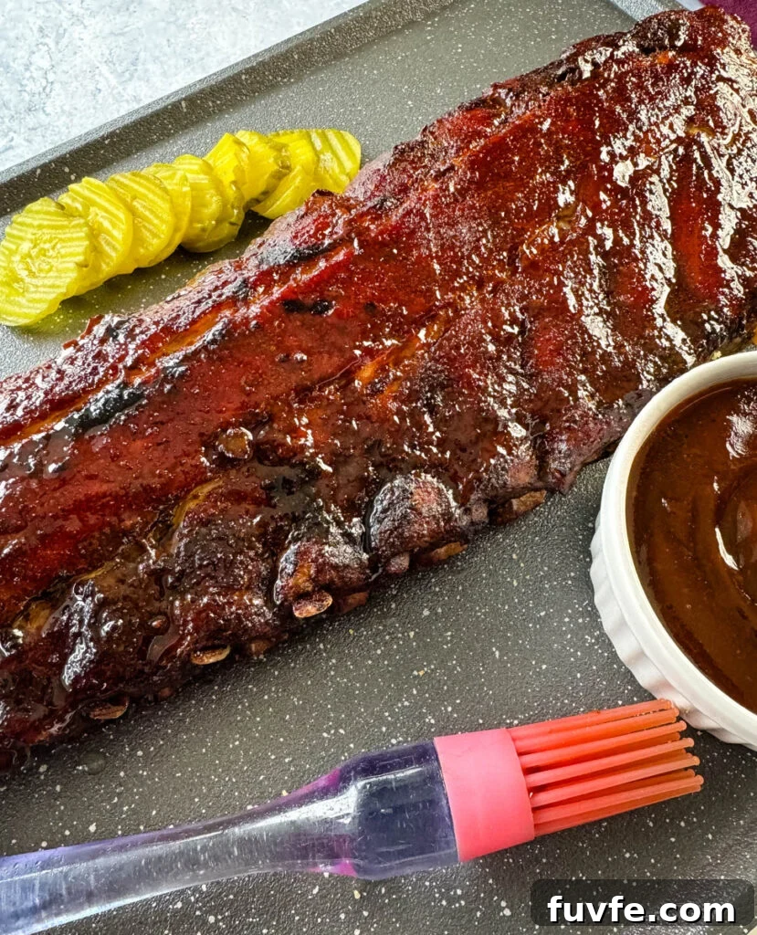 cooked ribs with BBQ sauce on a plate with pickles