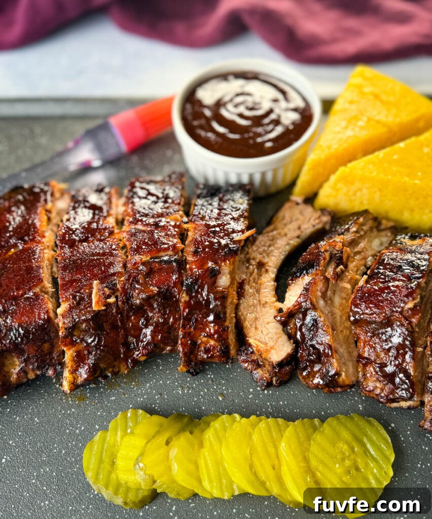 cooked ribs with BBQ sauce on a plate with cornbread and pickles